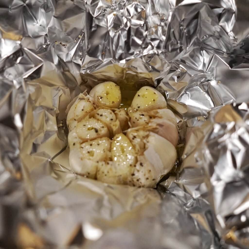garlic head with oil pepper and salt, on aluminum foil